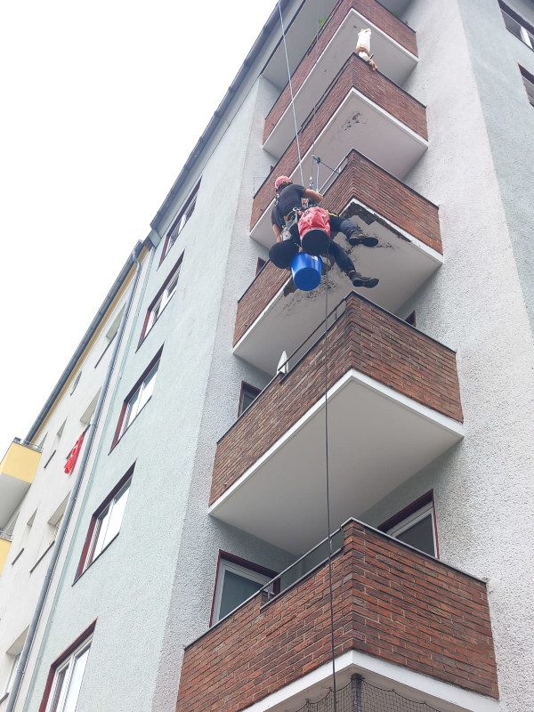 Zwei Techniker beim Abseilen an Balkonen zur Fassadensanierung