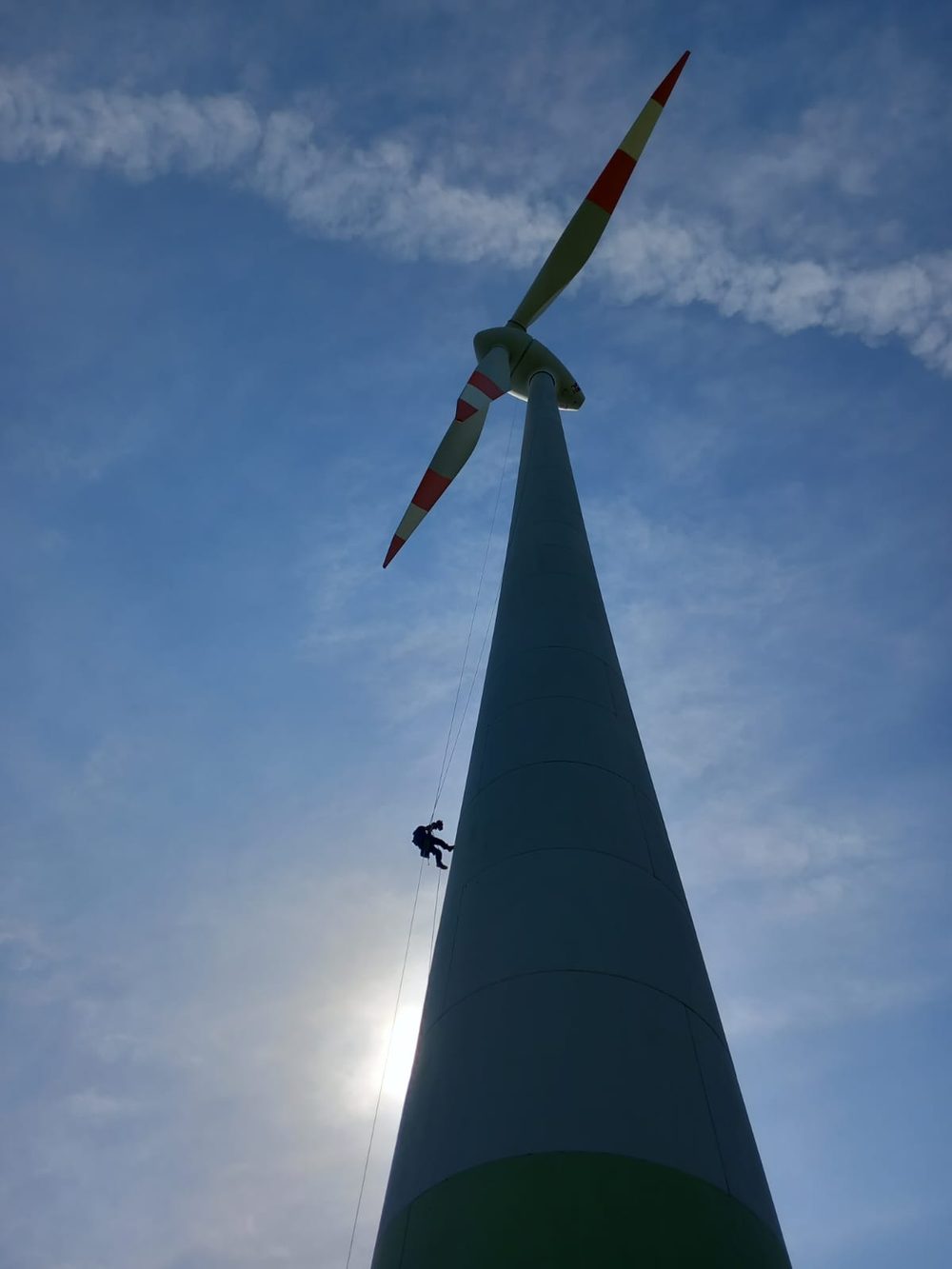 Technician rappelling down a wind turbine tower
