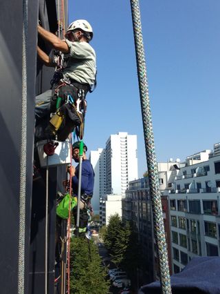 Two technicians descending a building facade