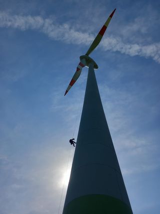 Technician rappelling down a wind turbine tower