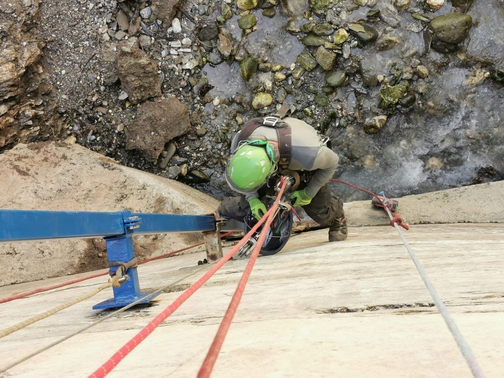 Rigging an anchor on a rock slab beside a river