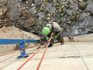 Rigging an anchor on a rock slab beside a river