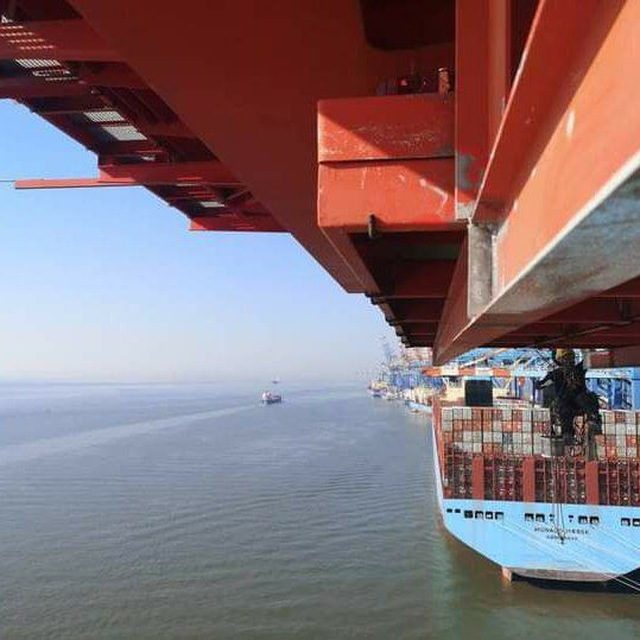 Vista por baixo de um braço de guindaste sobre um navio porta-contentores